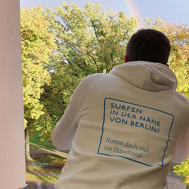 Matthias trägt weißen Hoodie mit blauem Spruch