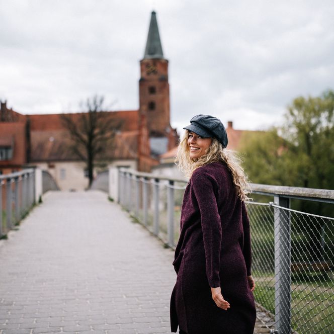 Frau läuft im Herbst über eine Brücke zum Dom St. Peter und Paul in Brandenburg an der Havel