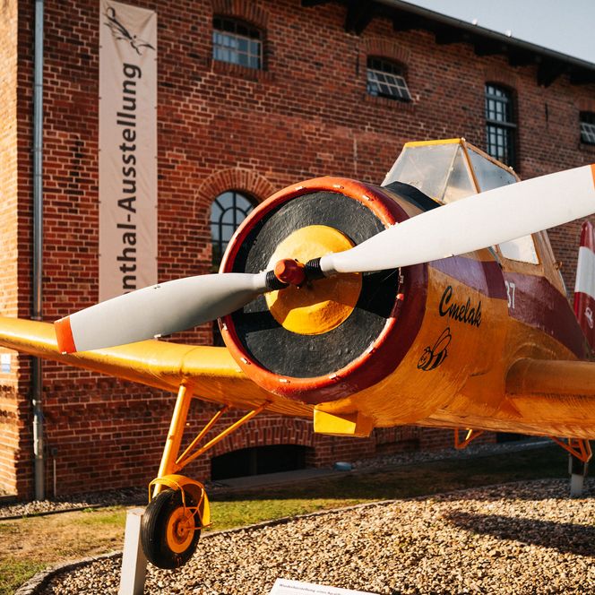 Gelbes Propellerflugzeug vor dem Otto-Lilienthal-Centrum Stölln