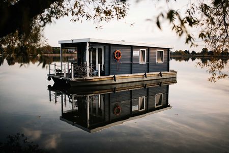Ein Hausboot liegt in der Dämmerung am Ufer des Beetzsees
