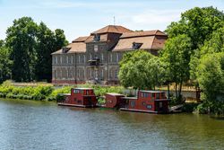 Blick auf Schloss Plaue mit Hausbooten am Anleger