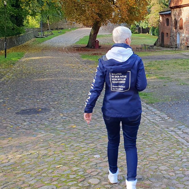 Carina trägt blaue Regenjacke mit weißem Spruch